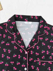 Détail d'un pyjama noir pour femme avec un imprimé de cerises roses et col à revers