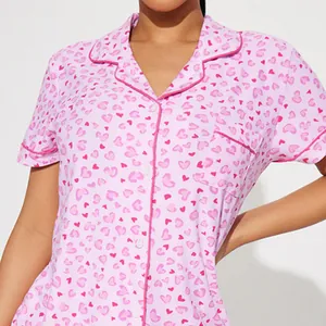 Pink women's pajama set featuring all-over heart print with lapel collar and buttons