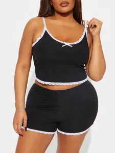 Detail von schwarzem Pyjama-Set in Übergröße mit weißem Spitzenbesatz und Schleife.
