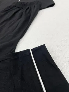 Gros plan d'un pantalon de pyjama d'été noir avec passepoil blanc élégant sur maille douce.