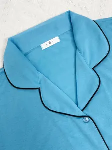 Gros plan du revers d'un pyjama bleu clair avec passepoil noir et étiquette de taille S.