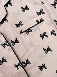 Detail view of soft pink pajama top featuring cute black bow prints and pocket