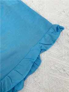 Gros plan sur le détail délicat de l'ourlet à volants d'un pyjama d'été bleu clair.