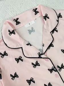 Close-up of pink women's pajama top with black bow print and lapel collar
