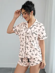 Detailed view of pink women's pajama set with black ribbon print and contrast piping
