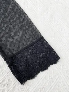 Detailed macro view of black floral lace cuff and semi-sheer mesh pajama sleeve texture