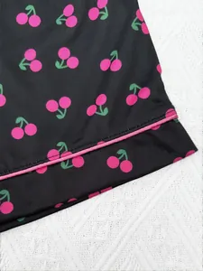 Gros plan sur le motif cerise rose vif et le liseré sur un ourlet de pyjama noir