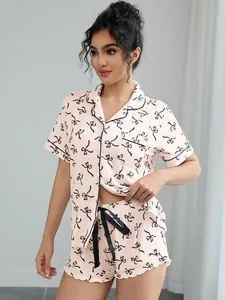 Detail of pink two-piece pajama set with black bow print and contrast piping trim.