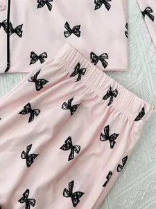 Detail view of pink women's pajama set with black bow-knot prints on soft fabric.