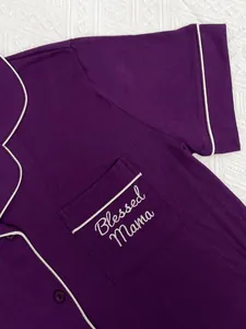 Gros plan sur la poche du pyjama violet avec broderie 'Blessed Mama' et passepoil blanc