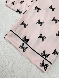 Close-up detail of pink long-sleeved pajamas with black bow print and soft fabric