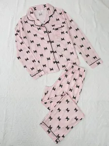 Detailed flat lay view of a pink long-sleeve pajama set with elegant black bow prints.