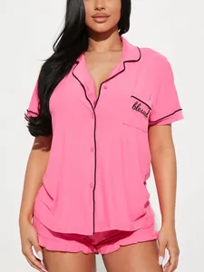 Détail du haut de pyjama rose doux avec passepoil noir et broderie personnalisée