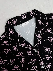 Détail d'un haut de pyjama noir avec imprimé nœud rose et col à revers de style classique
