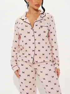 Close-up detail of women's pink pajama top with black bow print and lapel collar
