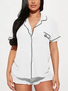 Gros plan du haut de pyjama blanc avec liseré noir et broderie blessed
