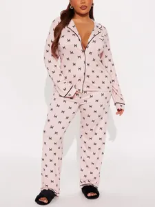 Two-piece pink silk-like pajamas set with long sleeves, lapel, and elegant black bow print