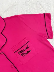 Gros plan du haut de pyjama rose avec broderie Blessed Mama et bordures noires fines