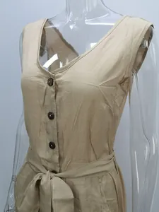 Detailed view of women's beige V-neck jumpsuit featuring front buttons and a bow tie waist