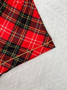 Gros plan détaillé du tissu à carreaux rouge et noir avec passepoil doré sur l'ourlet du pyjama