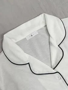 Vue détaillée d'un haut de pyjama blanc avec liseré noir et étiquette de taille