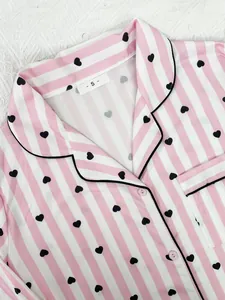 Detailed close-up of pink striped pajama top with black heart print and size label - S -