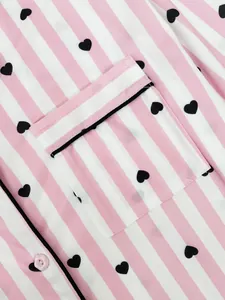 Macro view of pink and white striped pajamas with black heart print and pocket detail