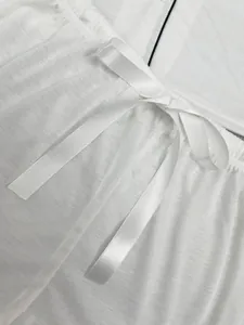 Détail de pyjama blanc pour femme avec nœud en ruban de satin à la taille élastique