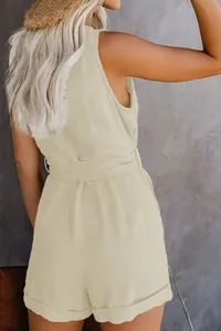 Back view of a chic beige sleeveless romper featuring a waist tie and cuffed shorts.