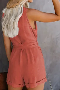 Back view of a coral red textured sleeveless jumpsuit with matching belt and cuffed hem