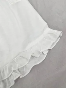 Gros plan sur le tissu blanc doux et l'ourlet à volants d'un ensemble pyjama femme