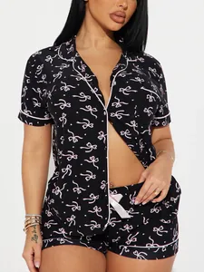 Détail de haut de pyjama noir à manches courtes avec un motif de nœuds roses imprimé