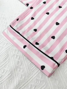 Detailed view of pink striped women's nightwear with black heart patterns and piping