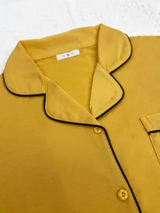 Gros plan d'un col de pyjama jaune pour femme avec liseré noir et boutons décoratifs