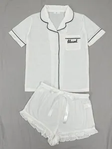 Détails d'un ensemble pyjama 2 pièces blanc avec broderie 'blessed' et volants.