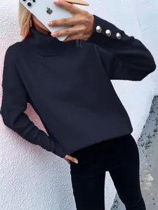 Close-up of navy blue high neck sweater with silver button cuff details in a casual style.