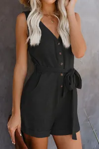 Detail view of black V-neck sleeveless romper with button front and tie waist belt.