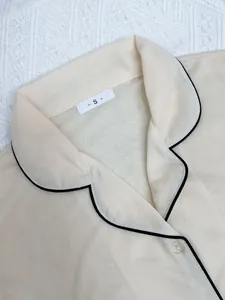 Vue détaillée d'un haut de pyjama crème pour femme avec liseré noir et étiquette de taille S