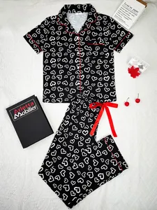 Close-up of black and white heart print pajama set featuring red piping detail
