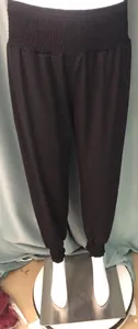 Full view of women's black loose harem pants with high elastic waist and cuffed ankles.