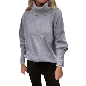 Loose fit grey turtleneck sweater for women with ribbed texture and decorative button cuffs.