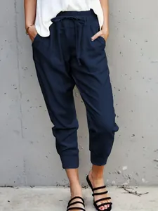 Close-up of navy blue cotton linen casual drawstring pants with a slim fit ankle-length cut.