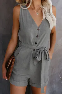 Close-up detail of a grey sleeveless V-neck jumpsuit featuring buttons and a bow tie waist.