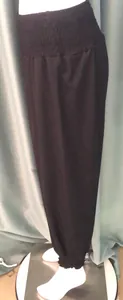 Detailed view of women's black harem pants with smocked waist and elastic cuffs