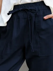 Close-up of navy cotton linen pants showing drawstring waist and pocket details.