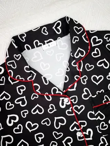 Close-up detail of women's black pajama top with white heart print and red piping accents