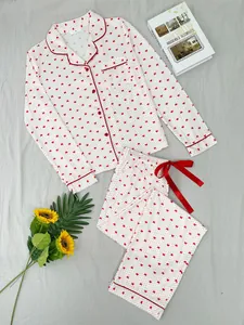 Flat-lay view of women's heart print pajama set with long sleeves and red bow tie