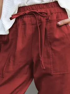 Close-up detail of red cotton linen trousers featuring drawstring waist and pockets