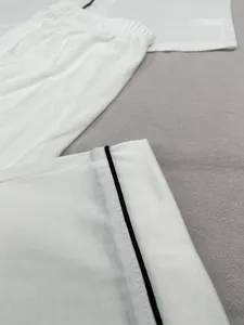 Vue détaillée en gros plan du pyjama blanc avec liseré noir contrasté et coutures précises
