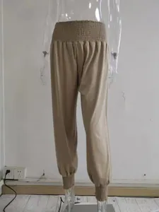Detailed view of khaki high-waisted harem pants with smocked waist and elastic cuffs.